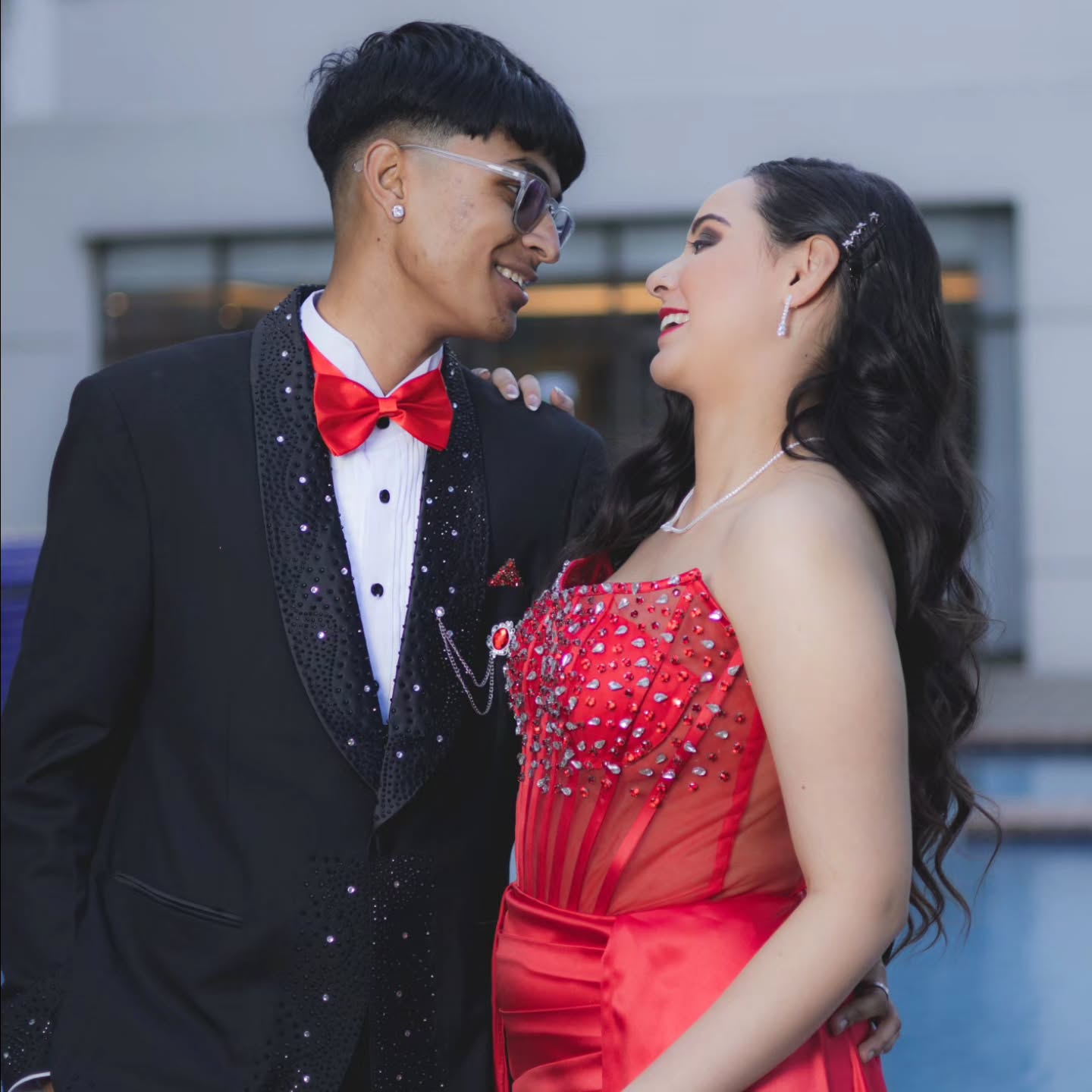 Couple portrait: partners in a suit and red gown facing each other