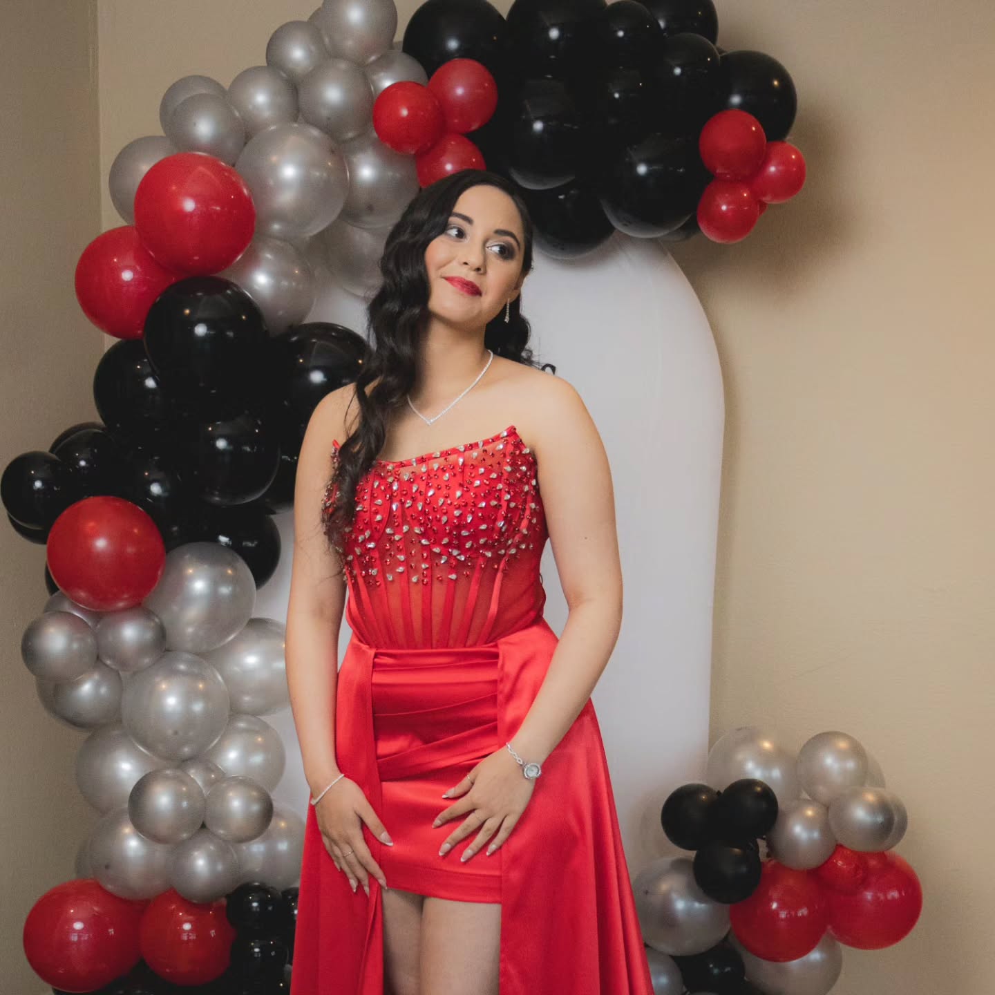 Event portrait: model in a red gown in front of a balloon arch